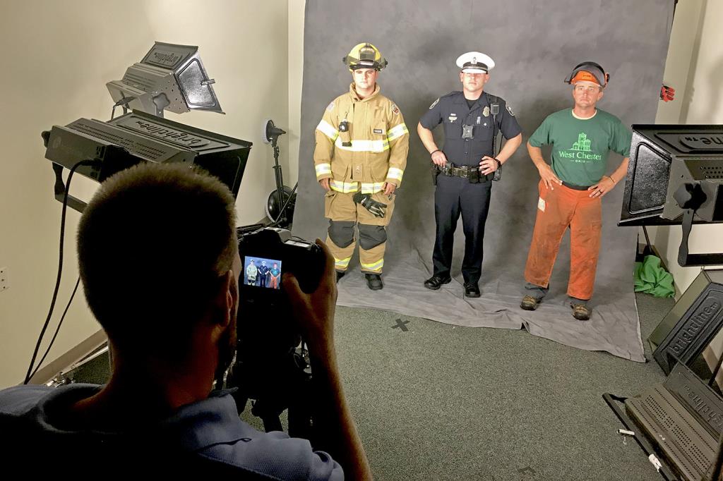 A photographer takes a picture of a West Chester firefighter, police officer and public works employee during a photos shoot.